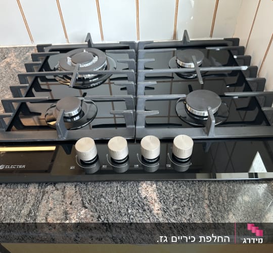 כיריים גז שחורות עם ארבעה מבערים וכפתורי שליטה